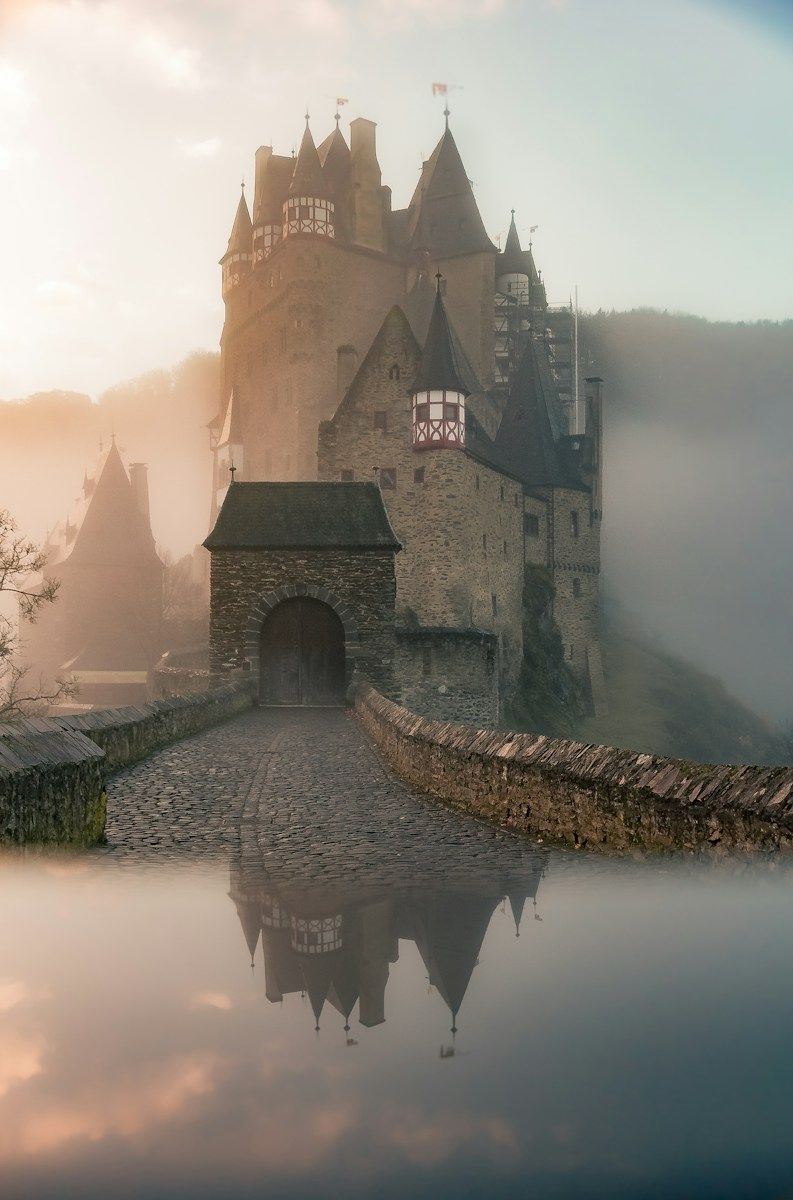 Eltz Castle in Wierschem, Germany, with a stone bridge and misty golden light